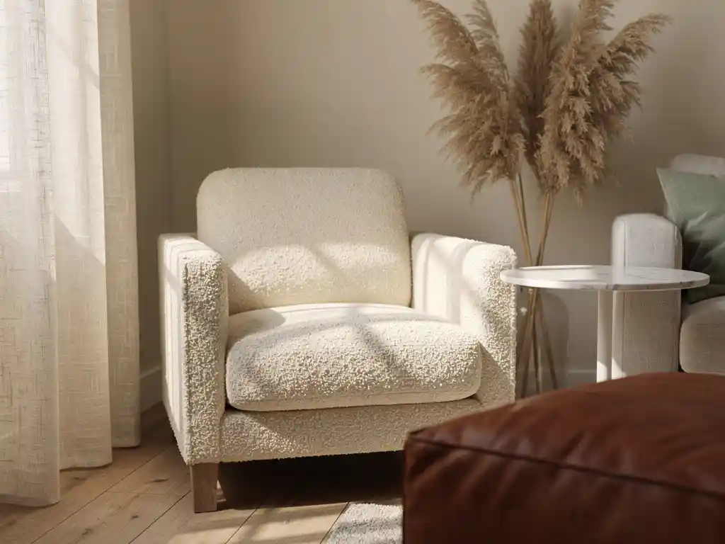 Ivoren bouclé fauteuil in Nederlandse woonkamer met marmeren bijzettafel, pampasgras en linnen gordijn in middaglicht.