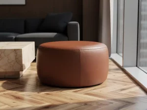 Cognac leren pouf op visgraatparket naast marmeren bijzettafel in een stijlvolle corporate lounge met natuurlijk licht.