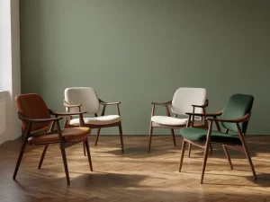 Collectie iconische designerstoelen van hout, leer en geweven stof op eiken visgraatparket, met zacht daglicht en saliegroen.
