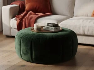 Ronde fluwelen poef als salontafel met dienblad, keramische kaars en boekjes, naast linnen bank met wollen plaid in terracotta en bosgroen.
