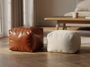 Cognacbruine leren poef naast een linnen poef in naturelcrème op een eiken visgraatparket in een Nederlandse woonkamer.